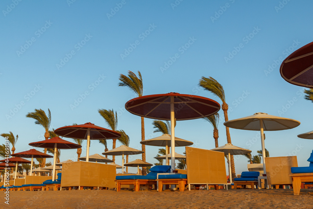 Beach with umbrellas and sunbeds against the blue sky.