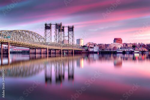 The I-5 Interstate Bridge at sunrise with purple and pink clouds reflecting in the Columbia River - Portland, Oregon to Vancouver, Washington