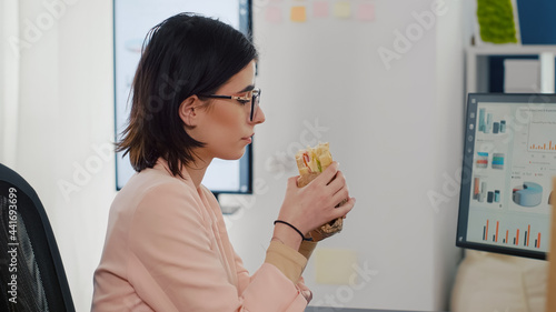 Quadro su tela Entrepreneur woman eating tasty sandwich having meal break working in business company office during takeout lunchbreak
