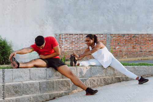 young male and female couple stretching on a sunny day, practicing sport, healthy lifestyle