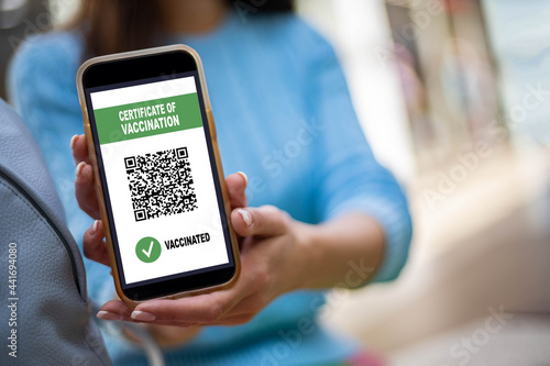 Portrait smiling woman posing with vaccine certificate on smartphone screen. Coronavirus prevention