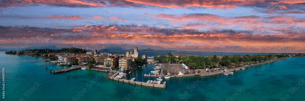 Aerial panorama of Sirmione castle at sunset, Lake Garda, Italy. Pink clouds over Sirmione, Lake Garda in Italy. Italian castles Scaligero on the water. Top view of the 13th century castle.