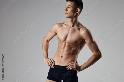 a guy with a pumped-up torso in black panties keeps his hands on his belt