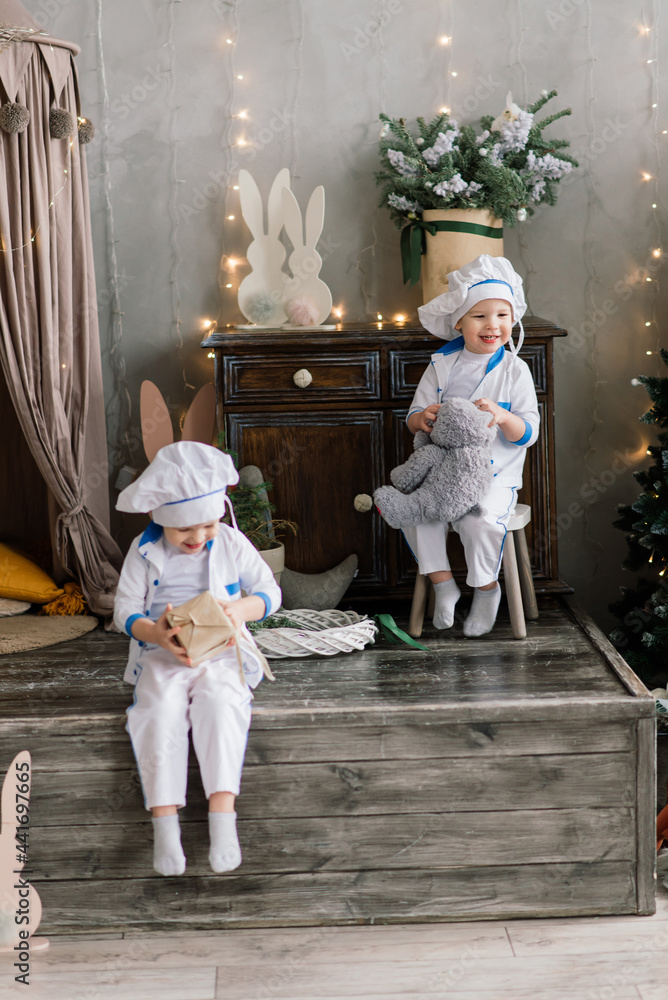 Happy funny two brothers bake christmas cookies near tree. Happy funny two brothers bake christmas cookies near tree.