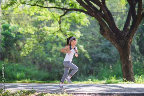 happy child girl running in the park in summer in nature. warm sunlight flare. asian little is running in a park. outdoor sports and fitness, exercise and competition learning for kid development.