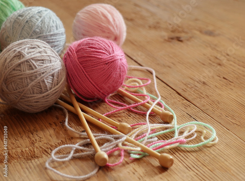 Colorful balls of yarn and knitting needles on wooden background