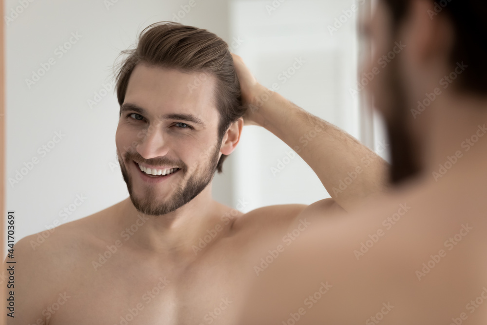 Happy attractive young guy touching smooth silky hair, looking at camera  from mirror with toothy smile. Handsome man enjoying haircare, satisfied  with shampoo, balm, haircut. Head shot portrait Stock Photo | Adobe