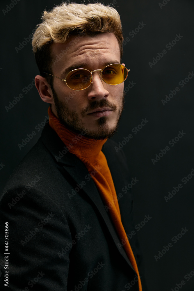 Fototapeta premium portrait of handsome blond man in jacket orange sweater on dark background 