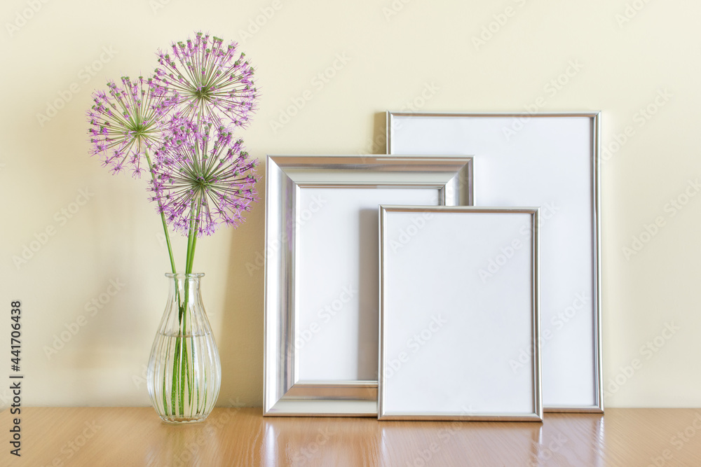 Mockup template with three silver frames and purple flowers in glass vase. Mockup template with three silver frames and purple flowers in glass vase.