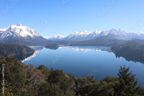 Beautiful snowy mountain chain reflected in the calm water of the lake with an astonishing blue cloudless sky above in Bariloche Argentina, amazing panoramic view in Circuito Chico Patagonia