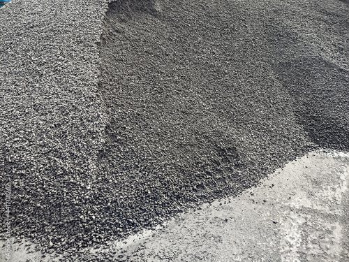 gravel on the dock ready to be loaded onto the ship. he tread of a large forklift truck on the gravel at the dock in the port. Bulk cargo in a heap at the berth for transportation by sea. 