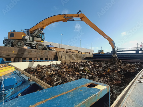 A loading and unloading crane unloads metal and metal waste from the ship's hold/ The grapple loading and unloading crane unloads metal and metal waste for recycling from the ship's hold