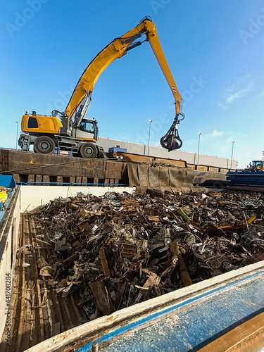 loading and unloading of scrap metal in the port/ Equipment in the port for loading and unloading operations for the disposal and recycling of scrap metal. Crane manipulator with gripper in the port f