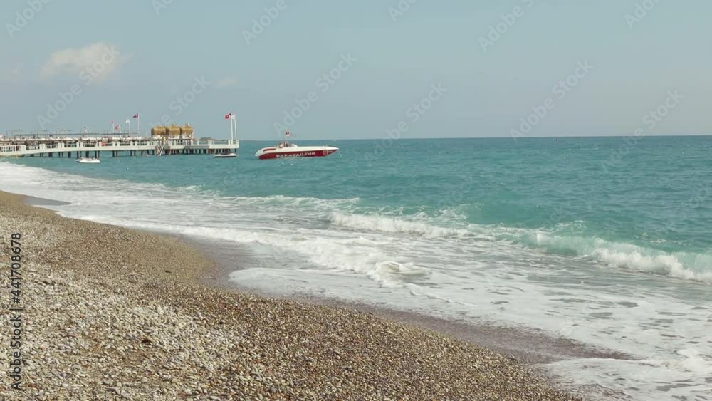 Beach in the Mediterranean Sea. Pebble. Visible on the pier and boat. Sea waves. Turkish flag Beach in the Mediterranean Sea. Pebble. Visible on the pier and boat. Sea waves. Turkish flag