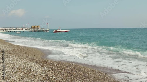 Beach in the Mediterranean Sea. Pebble. Visible on the pier and boat. Sea waves. Turkish flag
