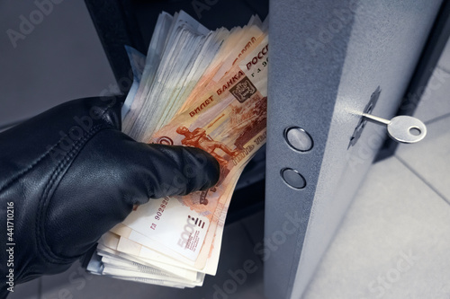 Fototapeta Robber's black-gloved hand pulls out wad of Russian rubles money from safe