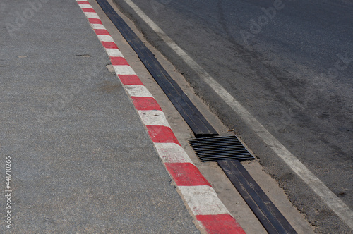 Footpath road. Red and white concrete sidewalk . View of Circuit. racetrack with white lines. White and red striped Parking Sign on Footpath road. © Shinpanu