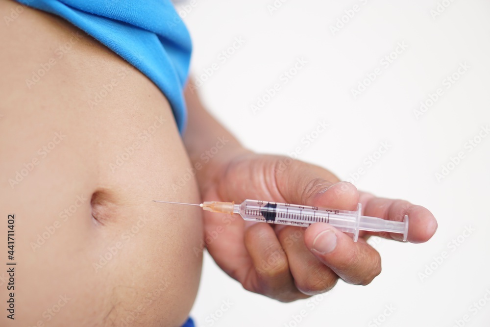 Concept : Insulin diabetic injection. Diabetic patient's hand is using syringe to inject insulin into his abdomen for control diabetes. Self care at home. Selective focus on syringe. Concept : Insulin diabetic injection. Diabetic patient's hand is using syringe to inject insulin into his abdomen for control diabetes. Self care at home. Selective focus on syringe.