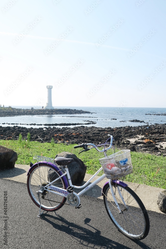 A bicycle was parked at the side of the road on Udo Island, with lighthouse as background in the picture