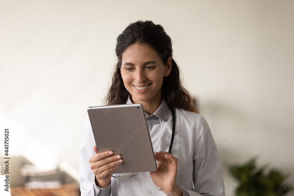 Smiling female nurse use modern table gadget in modern private hospital. Happy Caucasian woman doctor or therapist look at pad screen have webcam online digital video call with patient on device. Smiling female nurse use modern table gadget in modern private hospital. Happy Caucasian woman doctor or therapist look at pad screen have webcam online digital video call with patient on device.