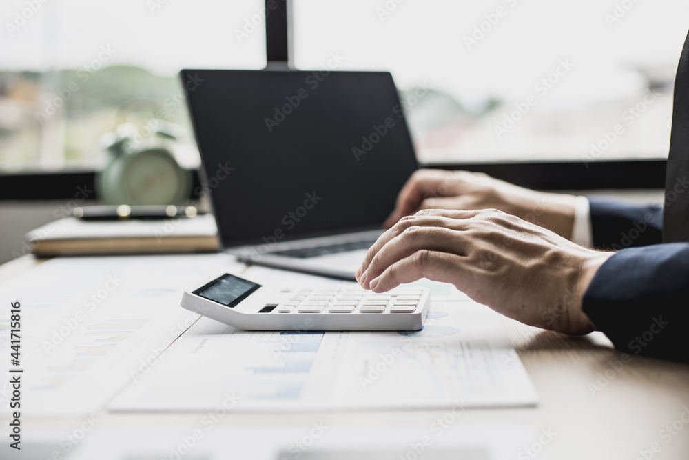 Man pressing white calculator, business man sitting in a private office at his company, he runs a startup company, he's a young man starting a business. Management concept of startup company. Man pressing white calculator, business man sitting in a private office at his company, he runs a startup company, he's a young man starting a business. Management concept of startup company.