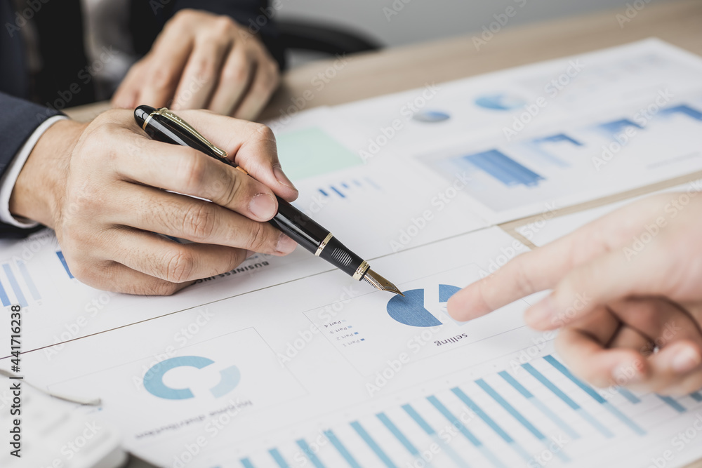 Two businessmen pointing at a chart on the document, they are startup friends together, business partners shaking hands after brainstorming and planning a startup company. Startup company concept. Two businessmen pointing at a chart on the document, they are startup friends together, business partners shaking hands after brainstorming and planning a startup company. Startup company concept.