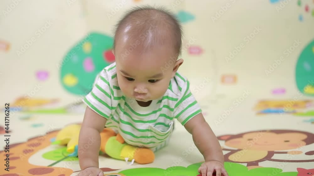 6 months old baby boy lying and playing on a colorful playmat