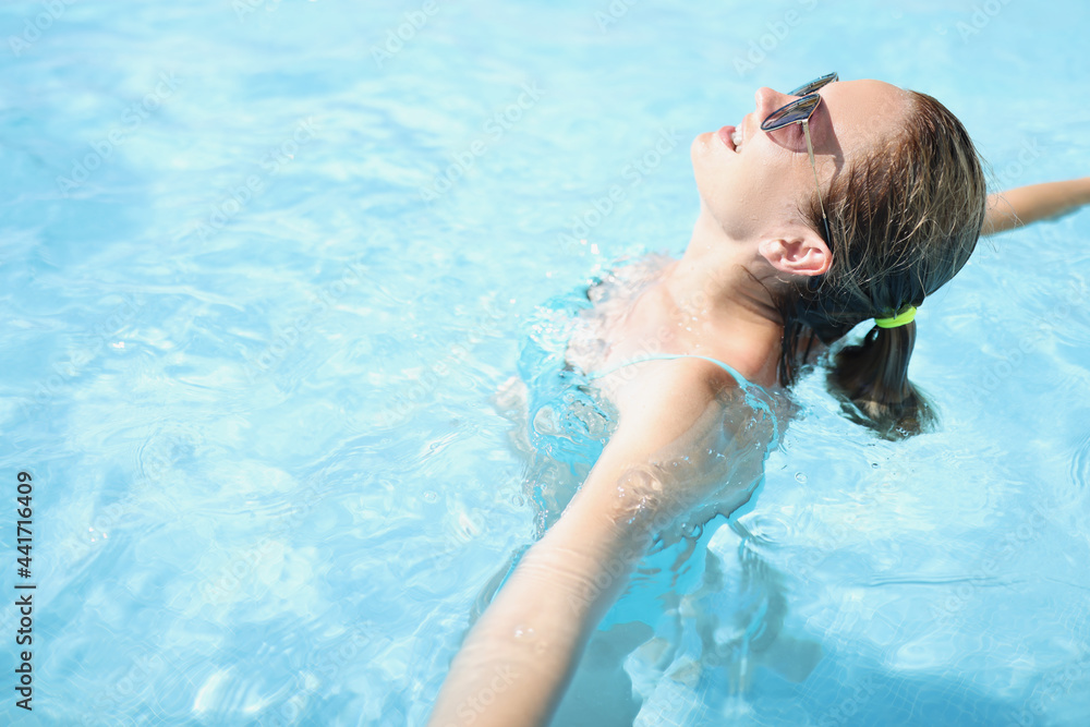 Young woman in sunglasses is enjoying vacation in pool closeup
