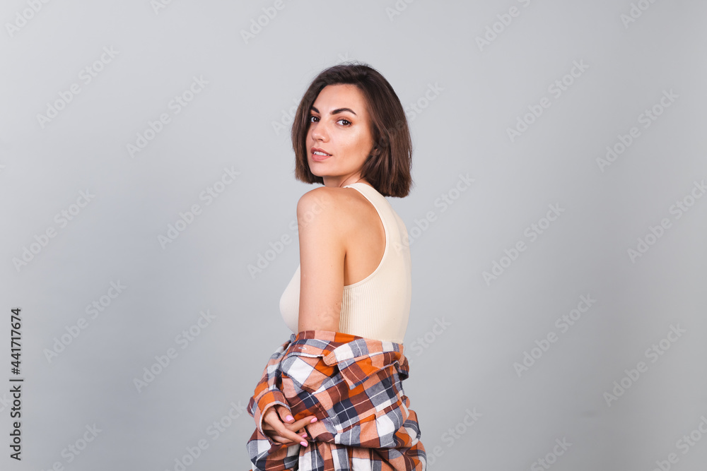Beautiful woman in top and plaid shirt on gray background with makeup positive confident smile, happy emotions Beautiful woman in top and plaid shirt on gray background with makeup positive confident smile, happy emotions