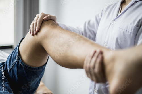 A professional physiotherapist is stretching the patient s legs  the patient has muscle dysfunction due to hard work  most often an office worker who has problems sitting for long periods of time.