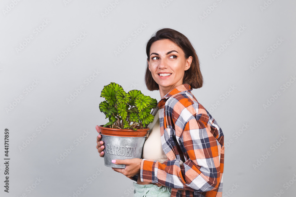 Beautiful woman in plaid shirt on gray background holds plant in hands, garden concept happy positive smile Beautiful woman in plaid shirt on gray background holds plant in hands, garden concept happy positive smile