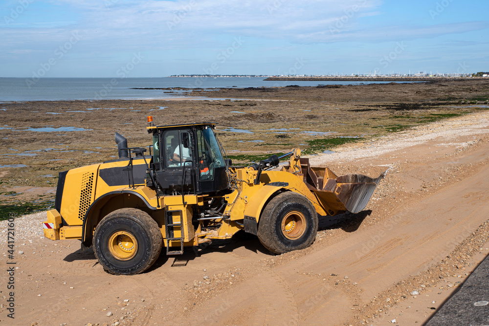 A construction excavator prepares a beach in Brittany for the arrival of tourists
A construction excavator prepares a beach in Brittany for the arrival of tourists