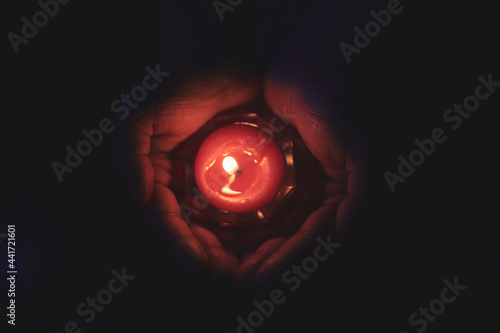 Burning candle in the hands of a girl. Christmas candles. Candle light glowing in woman's hands. Praying, faith, religion concept.