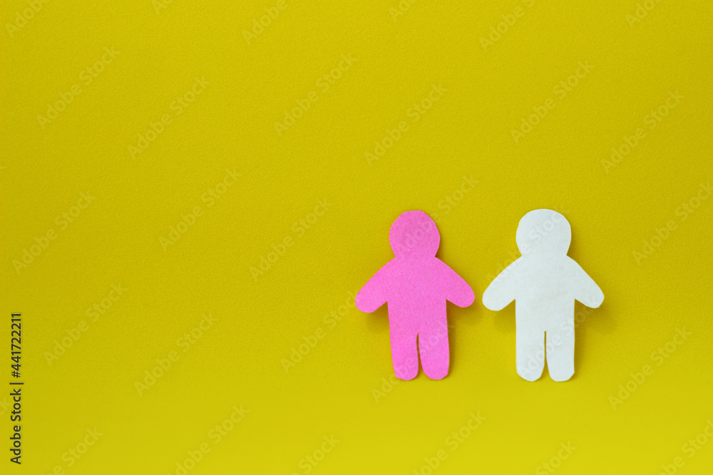Two silhouettes of a people carved from white and pink paper on yellow background. On right side of photo with copy space. Concept of communication, relationships, love, teamwork Two silhouettes of a people carved from white and pink paper on yellow background. On right side of photo with copy space. Concept of communication, relationships, love, teamwork