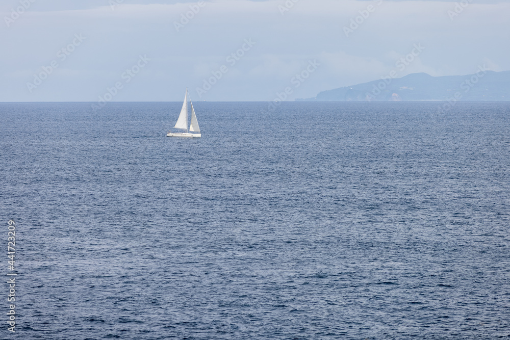 Fototapeta premium 伊豆半島沖の穏やかな海を帆走する白いヨットと伊豆大島