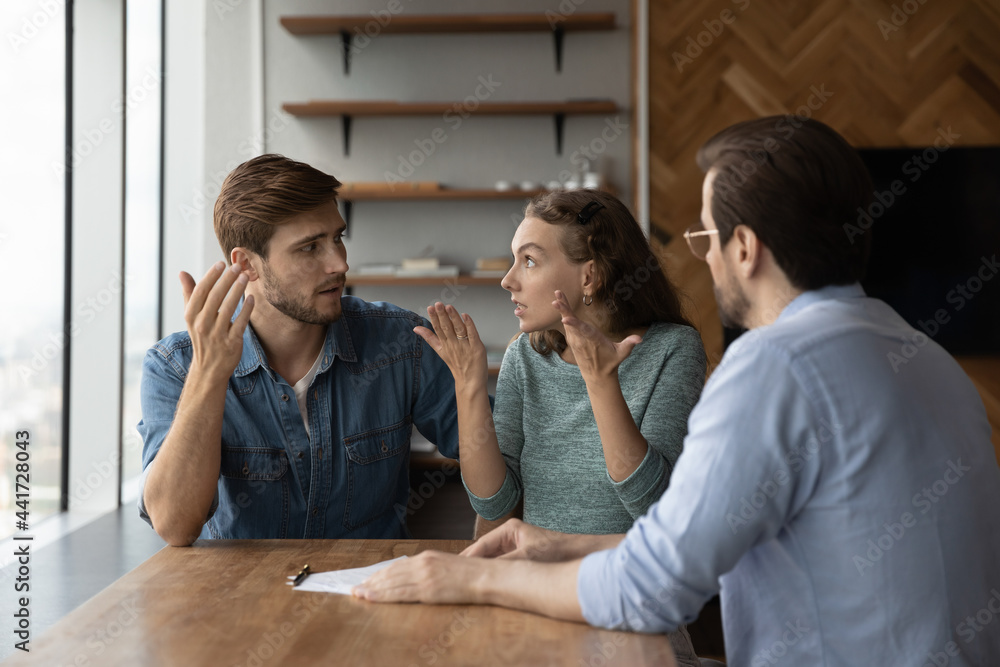 Stressed young family couple arguing, feeling dissatisfied with professional consultation or offer. Unhappy displeased clients demanding compensation or having misunderstanding at office meeting. Stressed young family couple arguing, feeling dissatisfied with professional consultation or offer. Unhappy displeased clients demanding compensation or having misunderstanding at office meeting.