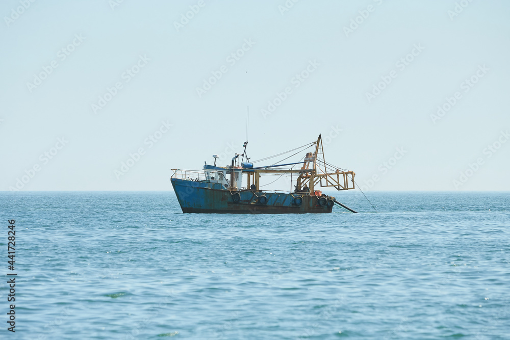 Fishing boat, trawler fishing Razor fish in an open Irish sea. Food industry, traditional craft, environmental damage concepts.