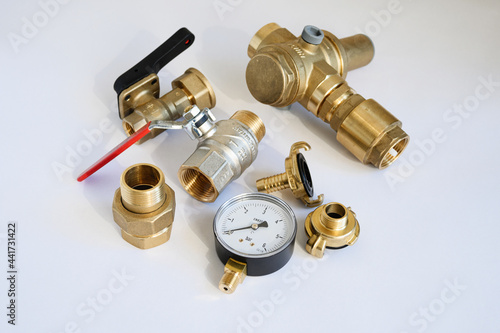 Brass accessories for water supply, water supply and irrigation: pressure gauge, fittings, on a light gray background