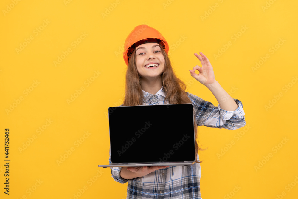 happy teen girl in helmet and checkered shirt presenting laptop, ok happy teen girl in helmet and checkered shirt presenting laptop, ok