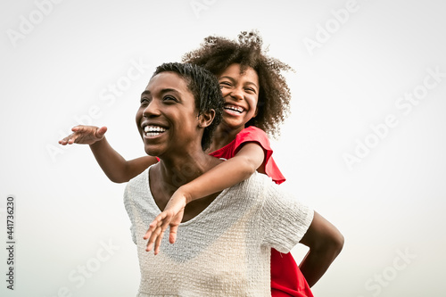 Happy African family on the beach during summer holidays - Afro people having fun on vacation time - Parents love and travel lifestyle concept