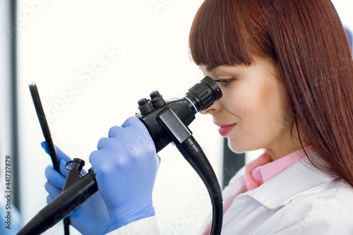 Foto Instrument for endoscopy in the hands of pretty young Caucasian female doctor, performing gastrointestinal fiberoptic endoscopy