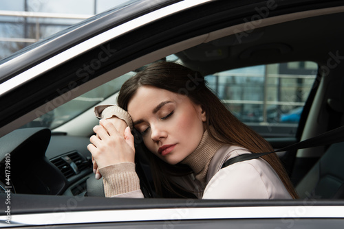 young exhausted woman sleeping in car at steering wheel