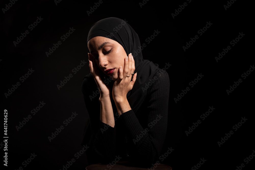 Gorgeous Muslim woman in black headscarf touching face Gorgeous Muslim woman in black headscarf touching face