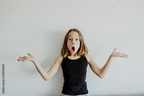 Excited girl making grimace against white wall