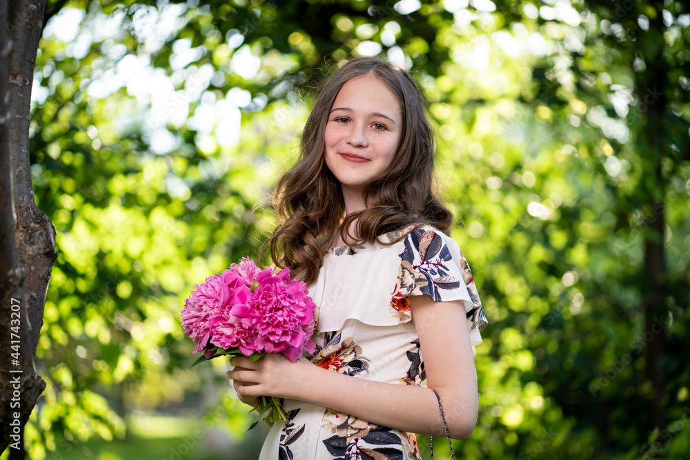 cheerful girl in a light summer dress against the background of a city park cheerful girl in a light summer dress against the background of a city park