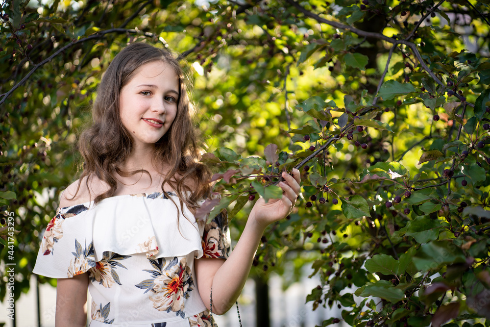 cheerful girl in a light summer dress against the background of a city park cheerful girl in a light summer dress against the background of a city park