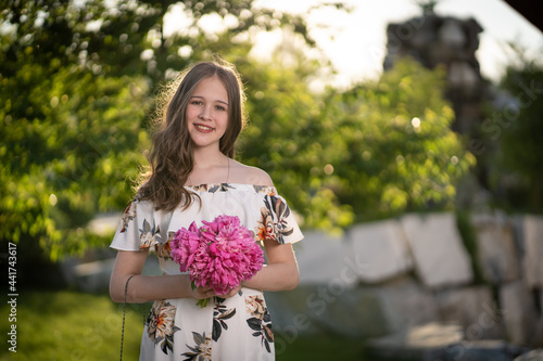 cheerful girl in a light summer dress against the background of a city park