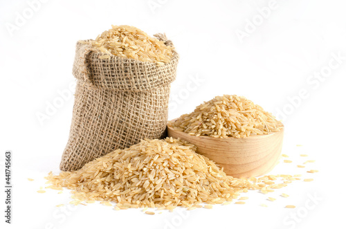 Dry brown rice seed pile in sack and wooden bowl on white background, for carbohydrate food raw material or agricultural product concept