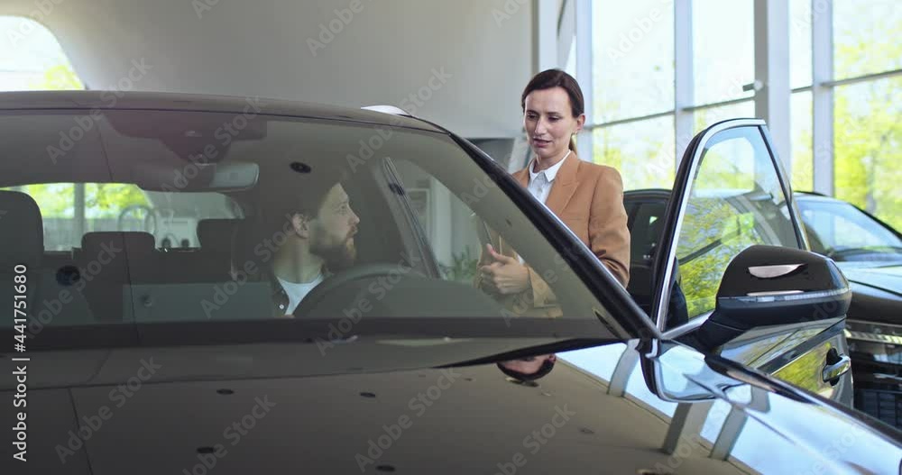 Showroom car, buyer sit in automobile and test it. Sales manager car agent tell man client about steering wheel. Showroom car, buyer sit in automobile and test it. Sales manager car agent tell man client about steering wheel.