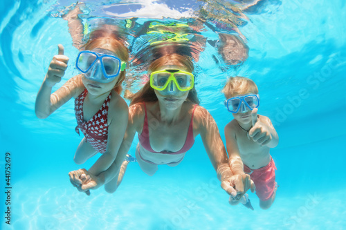 Happy people dive underwater with fun. Funny photo of mother, kids in snorkeling masks in aqua park swimming pool. Family lifestyle, children water sport activity, lesson with parent on summer holiday